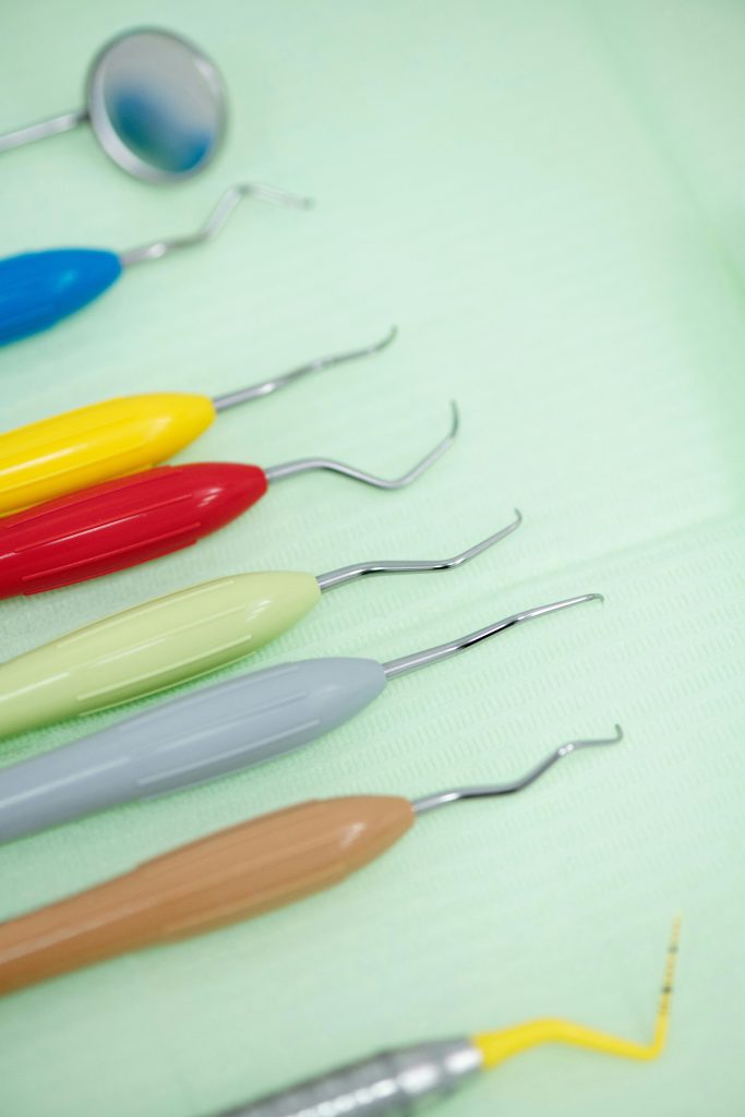 Close-up of colorful dental tools arranged on a green cloth, emphasizing dental care.